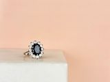 a close up of a black and white diamond ring on top of a marble block