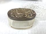 a small glass box with a silver lid on a table