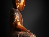 a statue of a buddha sitting on a black surface