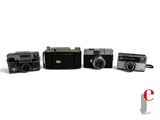 several old cameras are lined up in a row on a white surface