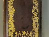 an old book with a gold decoration on it sitting on top of a table