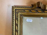 a gold framed mirror with a bow on top of it