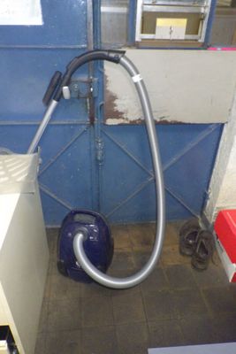 une photo d'une pièce avec un aspirateur et une poubelle