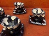 quatre tasses et soucoupes noires et blanches posées sur une table
