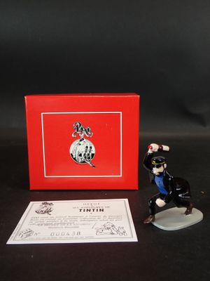 La figurine est posée à côté d'une boîte rouge sur une table noire.