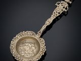 an ornate silver spoon with a handle and handle on a black surface