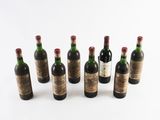 six bottles of wine lined up in a row on a white surface