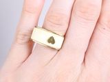 someone is holding a gold ring with a heart on it