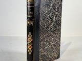 an old book sitting on top of a table next to a white wall