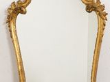 une image d'un miroir encadré d'or sur un mur blanc