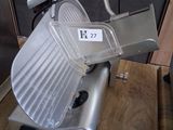 a large meat slicer sitting on a wooden table