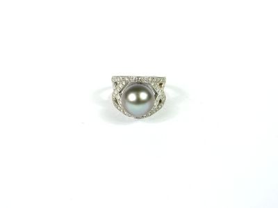 gros plan d'une bague en perles et diamants sur une surface blanche
