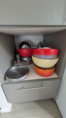 two bowls and pans sitting on a shelf in a kitchen