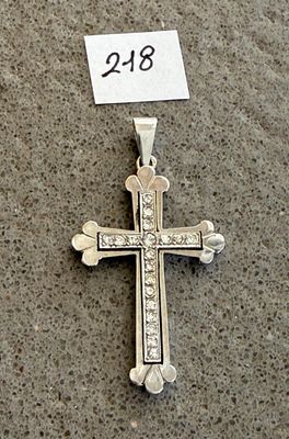 une croix en argent posée sur une table, avec une étiquette de prix accrochée dessus