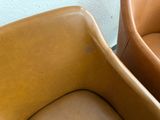 two leather chairs sitting next to each other on the floor