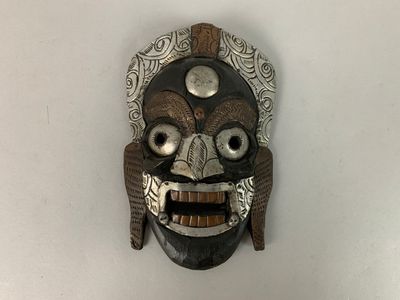 un masque en bois accroché à un mur blanc