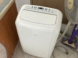 a small white air conditioner sitting next to a fan