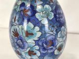 a blue and brown flowered egg sitting on a white surface