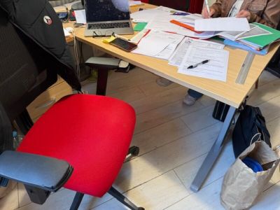 several people sitting at a table with laptops and papers on it