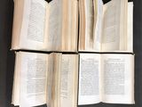 several open books on a table with a black background