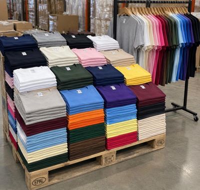 de nombreux t-shirts de différentes couleurs posés sur une palette dans un magasin