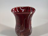 a red vase sitting on a white surface with a white background