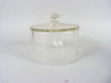 clear glass jar with gold trim and lid on a white surface