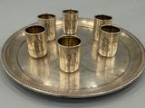 un plateau en argent sur lequel sont posées six tasses en argent