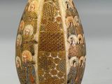 a gold vase with a picture of people on it