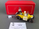 figurine of a yellow car with a skeleton in the driver ' s seat and a red box