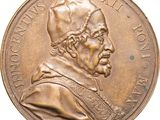 un gros plan d'une médaille sur laquelle figure un homme coiffé d'un chapeau