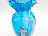 a blue glass vase with a small figurine inside of it