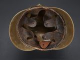 an old helmet with a hole in the middle of it on a black surface