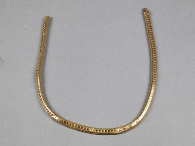 gros plan d'un collier en or sur une surface blanche