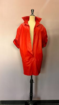 une veste en cuir rouge posée sur un mannequin devant un mur