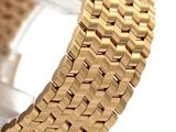 a close up of a gold watch bracelet on a white surface