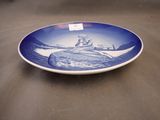 a blue and white plate with a picture of a man on a boat
