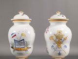deux vases blancs ornés de motifs dorés et bleus sur un fond gris