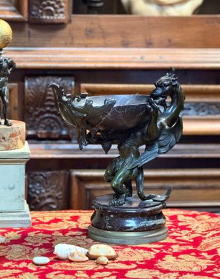 une statue représentant un homme et une femme, posée sur une table à côté d'un vase