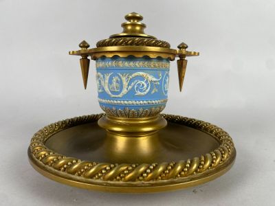 un plateau en or sur lequel est posé un vase bleu