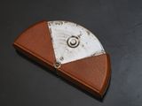 brown and white leather case with a metal ring on top of it