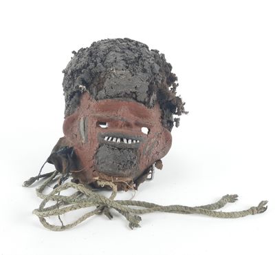 a clay mask with a face on it on a white surface