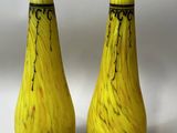 une paire de vases en verre jaune posés sur une surface blanche