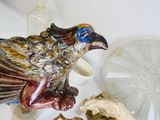 une figurine d'oiseau posée sur une table, à côté d'une horloge et d'autres objets