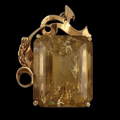un gros plan d'un pendentif doré orné d'une pierre jaune facettée