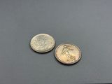 two coins sitting on top of a table next to each other