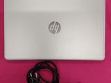 Ordinateur portable HP avec son cordon d'alimentation et son chargeur, posé sur une surface rose