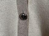 a close up of a white sweater with a button on it