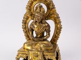une statue en or représentant un Bouddha assis sur une table