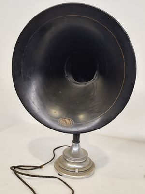 une enceinte noire posée sur une table, à côté d'une lampe